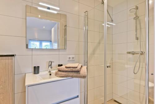 a bathroom with a shower and a sink and a mirror at Duin17 in Zoutelande