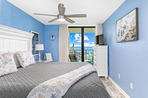 a bedroom with blue walls and a bed with a ceiling fan at Updated Beachfront 2 BR 2 Bath Condo with direct views of the beach in Orange Beach