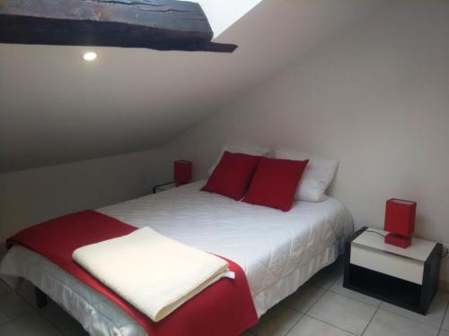 um quarto com uma cama branca e almofadas vermelhas em Appartement en location touristique pour 4 personnes em Docelles