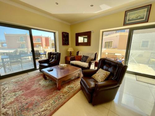 a living room with two chairs and a coffee table at Seaview Family Apartment, Pool, Easy Access to the Sea, Near Mellieħa Bay in Mellieħa