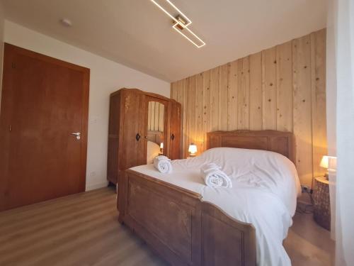 een slaapkamer met een groot bed met witte lakens en handdoeken bij Fête des jonquilles in Gérardmer