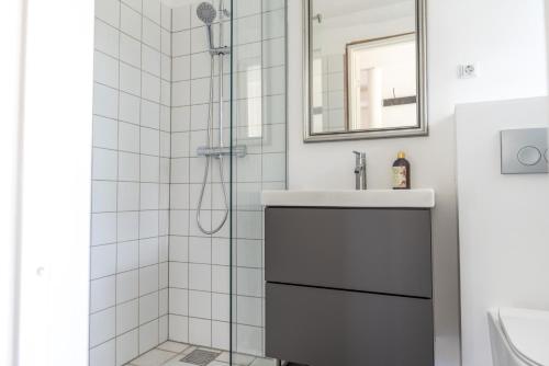 a white bathroom with a shower and a sink at Ferielejlighed Næstved in Næstved