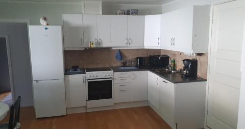 a kitchen with white cabinets and a white refrigerator at Nydelig utsikt, egen leilighet med to parkeringer in Movik