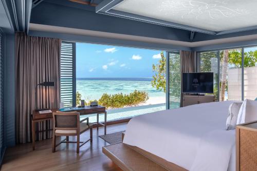 a bedroom with a bed and a view of the ocean at Raffles Maldives Meradhoo in Gaafu Alifu Atoll