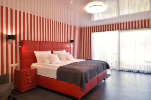 a bedroom with a red striped wall with a bed at TI Hotel in Rogaška Slatina