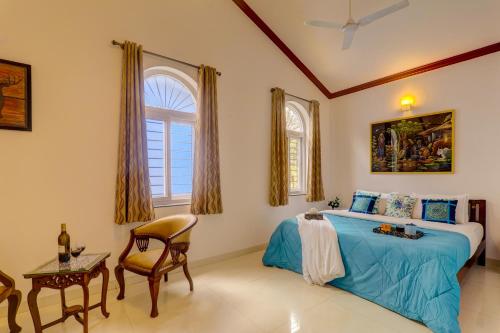 a bedroom with a blue bed and a chair at Ludo Private Pool Villa, WiFi-Caretaker-Parking, North Goa in Baga