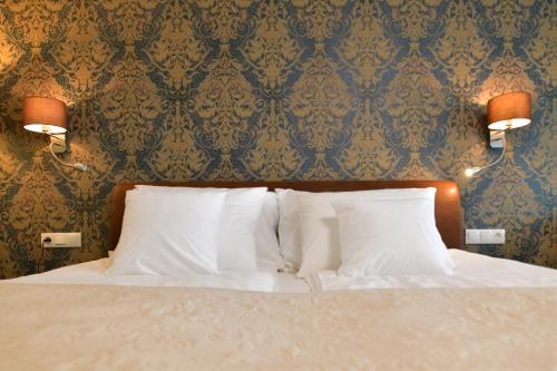 a bedroom with a bed with white pillows and a wallpaper at TI Hotel in Rogaška Slatina