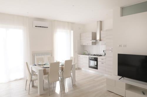 a white kitchen with a table and chairs and a television at Angela Apartment in Sorrento