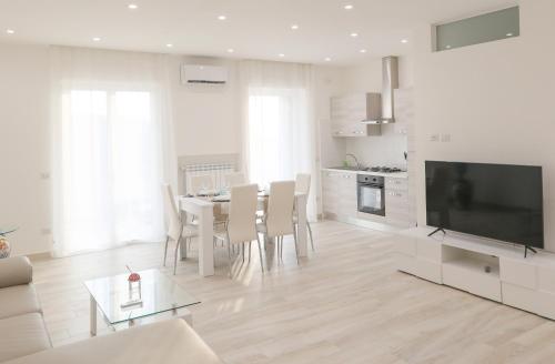 a white living room with a table and a television at Angela Apartment in Sorrento