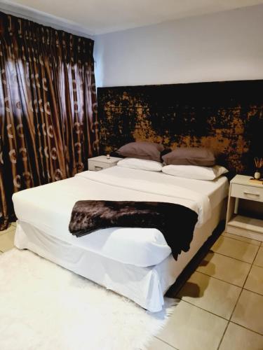 1 dormitorio con 1 cama grande y pared negra en Finna's lovely 1-bedroom open plan vacation home., en Germiston