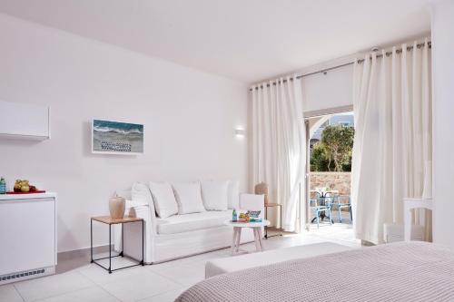 a white room with a white couch and a window at Santo Miramare Beach Resort in Perivolos