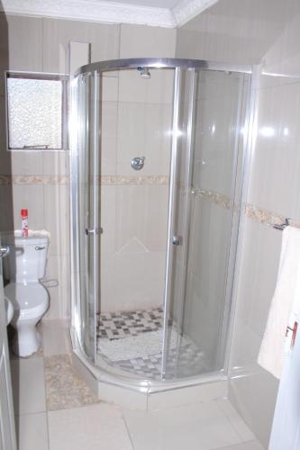 La salle de bains est pourvue d'une douche avec une porte en verre. dans l'établissement Global Guest House, à Kasane