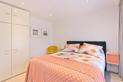a white bedroom with a bed with a orange blanket at Duin17 in Zoutelande