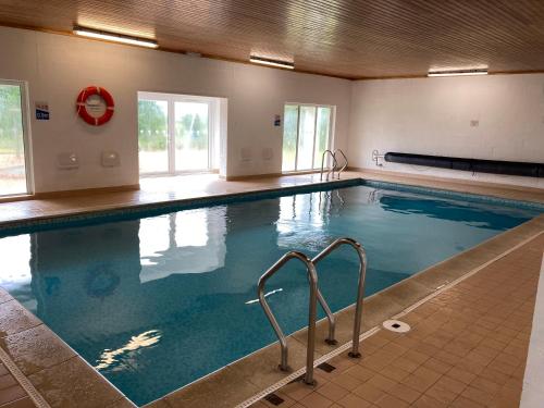 a large indoor swimming pool with blue water at Ploughmans Cottage, St Florence, Tenby in Tenby