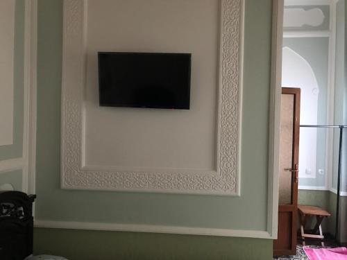 a flat screen tv on a wall with a mirror at Rahmat guesthouse in Bukhara