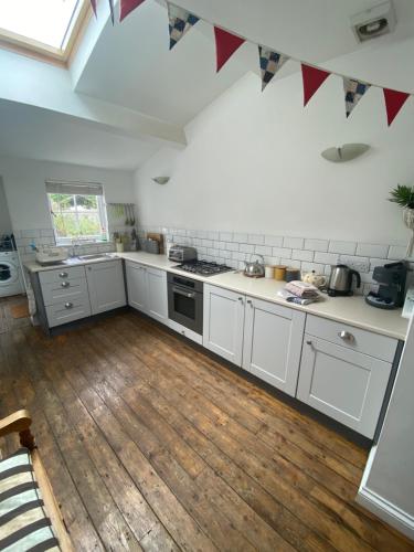 cocina con armarios blancos y suelo de madera en Fermaine, 50m from sea, garden, dogs, town centre, en Lyme Regis