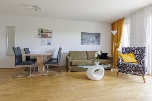 ein Wohnzimmer mit einem Sofa, einem Tisch und Stühlen in der Unterkunft Vienna City and SPA - Modern Apartments next to Therme Wien & 15 Minutes to the City Center in Wien