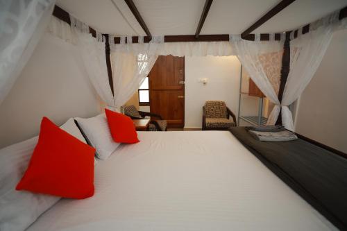 a bedroom with a large white bed with red pillows at Ayla Homes in Madikeri