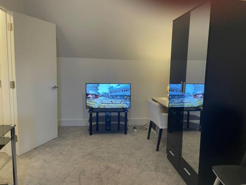a room with a desk and a flat screen tv at Rendezvous in Romford