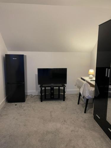a living room with a black piano and a table at Rendezvous in Romford