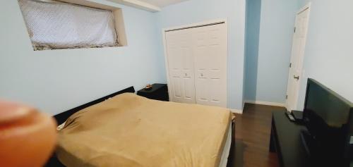 a room with a bed and a window and a television at Parson Creek Cozy suite in Fort McMurray