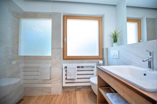 een badkamer met een wastafel, een toilet en een raam bij Apartments Cesa Ploner in Ortisei