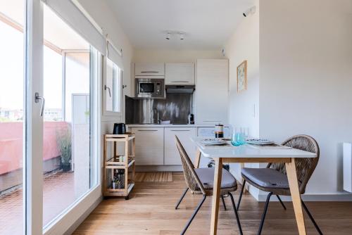 une cuisine avec une table et des chaises dans une pièce dans l'établissement LE NID DES CEDRES - Magnifique Studio terrasse Montplaisir, à Lyon