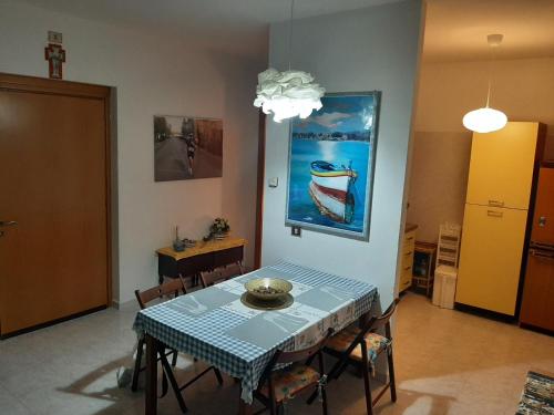 a dining room with a table and a painting of a boat at Casa vacanza Colle Renazzo con terrazzo in collina 15 min. dal mare in Mafalda