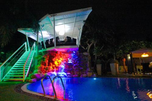 a swimming pool with a water slide and a fountain at night at Momento Resort in Pattaya South