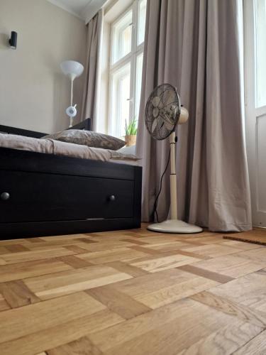 a bedroom with a bed and a fan on a wooden floor at Klimatyczny Apartament na Bydgoskim Przedmieściu in Toruń