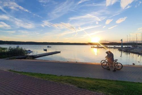 a person riding a bike on a path near a body of water at Dom na Zaciszu Charzykowy in Charzykowy