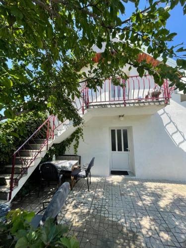 a house with a balcony and a table and chairs at Vikendica Vrba in Gacko
