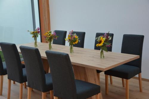 una mesa con sillas y jarrones con flores en Wachtelwerkstatt, en Unternalb