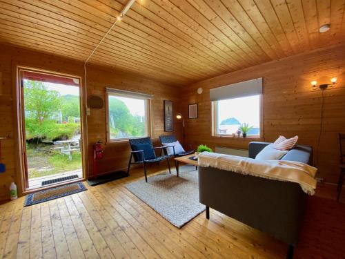 a room with a bed and a living room with windows at Haukland Camp Cabin in Leknes