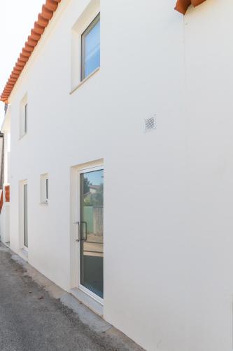 a white house with a door on a street at Cellar House - Casa do Palheiro in Miranda do Corvo