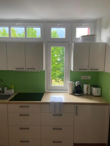 a kitchen with white cabinets and green walls at Bee's Place Holiday Home Kranjska Gora in Kranjska Gora