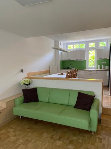 a living room with a green couch and a kitchen at Bee's Place Holiday Home Kranjska Gora in Kranjska Gora