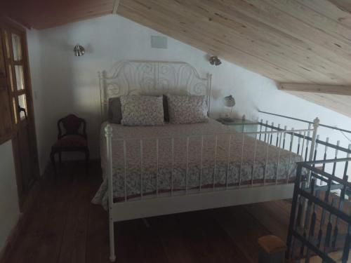 um quarto com uma cama branca num sótão em La caseta de El Llancís em L’ Esquirol
