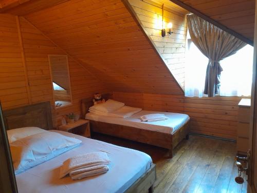 a bedroom with two beds in a wooden cabin at Pensiunea Trei Ponei in Corbeni