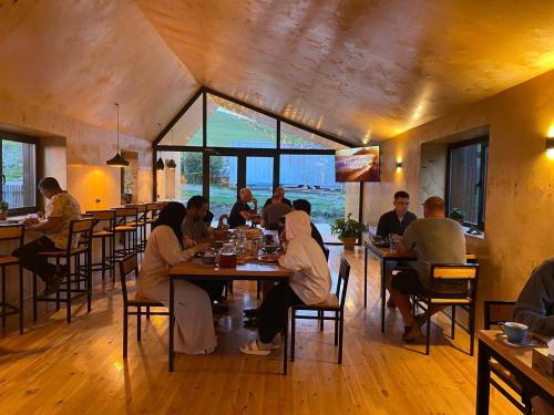 un groupe de personnes assises à table dans un restaurant dans l'établissement Peak Lodge Jyrgalan, à Dzhergalan