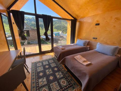 a room with two beds in a room with a window at Peak Lodge Jyrgalan in Dzhergalan