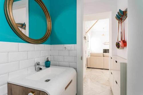 ein Badezimmer mit einem weißen Waschbecken und einem Spiegel in der Unterkunft Fantástico ático en el casco antiguo en a la playa in Cádiz
