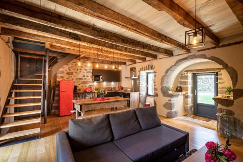 un salon avec un canapé et une cuisine dans l'établissement Maison typique des monts du Cantal, à Marmanhac
