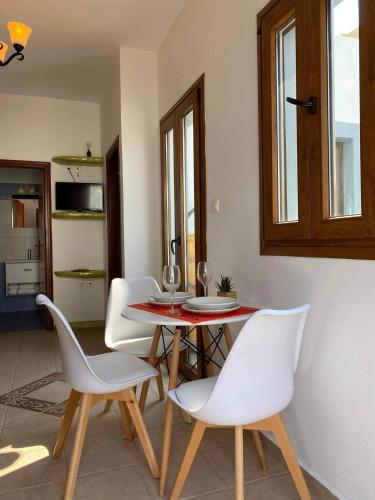 a dining room with a table and white chairs at Ammos 1 in Panteli