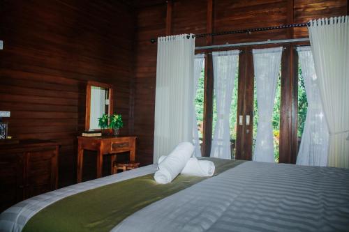 a bedroom with a bed and a window with white curtains at Kurnia Guest House & Spa in Nusa Penida