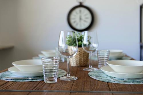 a table with wine glasses and plates and a clock at Ferienwohnung "Casa El Aberle" Modern eingerichtet in schöner Lage mit Parkplatz in Stockach