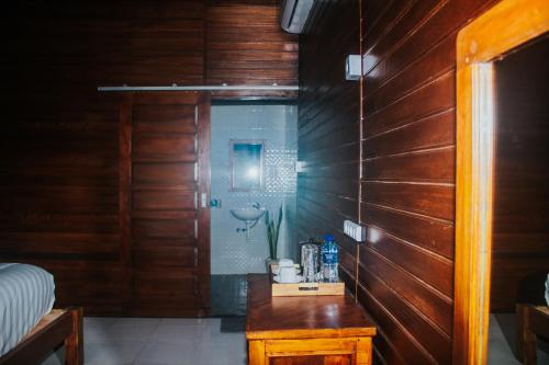 ein Bad mit einer Dusche und einer Holzwand in der Unterkunft Kurnia Guest House & Spa in Nusa Penida