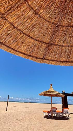 two chairs and an umbrella on a beach at Bel appartement pied sur mer vue imprenable sur piscine et jardins in Sidi Rahal