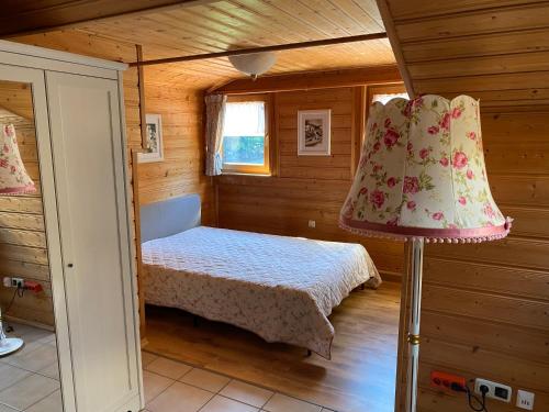 ein kleines Schlafzimmer mit einem Bett und einer Lampe in der Unterkunft Hüttenflair im Gut Sonnenwald in Schöllnach