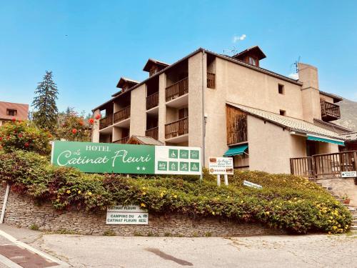 un bâtiment avec un panneau devant lui dans l'établissement Le Catinat Fleuri, à Guillestre